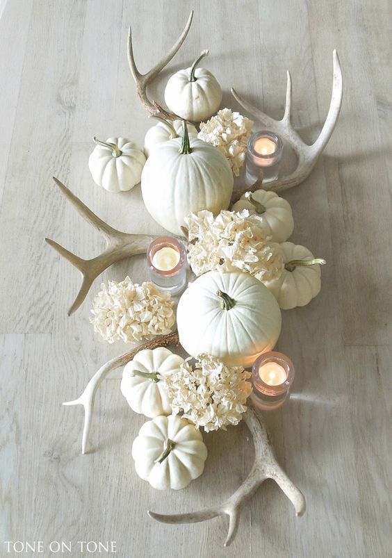 a neutral Thanksgiving centerpiece with white antlers, hydrangeas, pumpkins and candles will add a rustic touch to the space