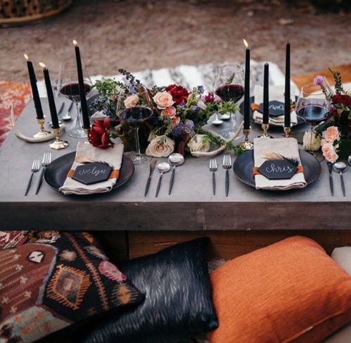 a gorgeous boho chic picnic setting for Halloween with lush florals, candles and black chargers