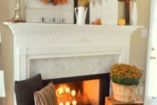 22 a mantel decorated with fall leaves, pumpkins and wheat and a fireplace with candles, pumpkins, fall blooms and lanterns