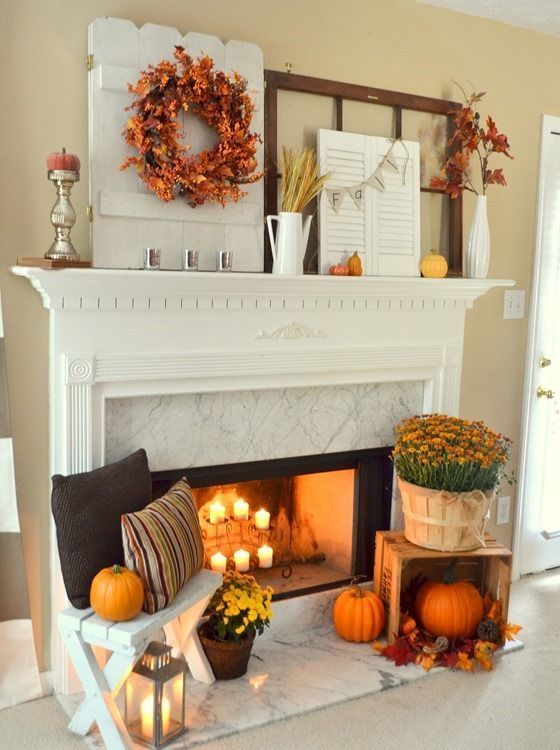 a mantel decorated with fall leaves, pumpkins and wheat and a fireplace with candles, pumpkins, fall blooms and lanterns