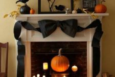 22 a natural fireplace and mantel with a black ribbon bow, fake birds, fall leaves on branches and lots of candles