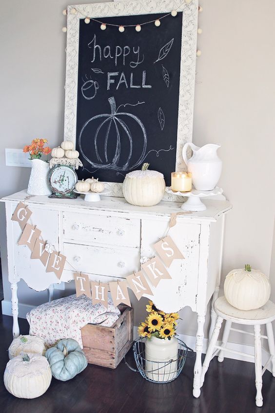 a neutral Thanksgiving console with a banner, heirloom pumpkins, little white ones and a jug