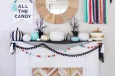 23 a colorful Halloween mantel with bright pompoms, tassels, pumpkins and various garlands