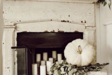 23 a very neutral fall fireplace and mantel, much greenery and white pumpkins and candles