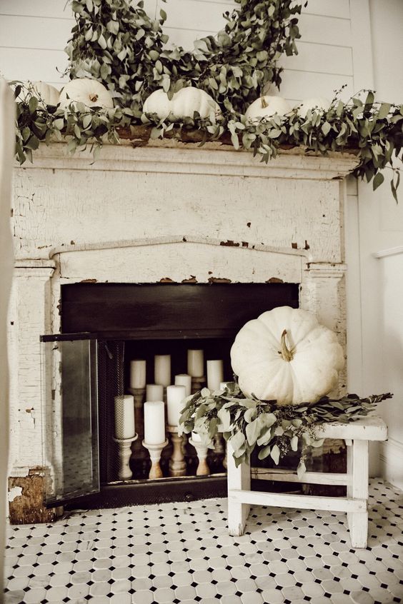 a very neutral fall fireplace and mantel, much greenery and white pumpkins and candles