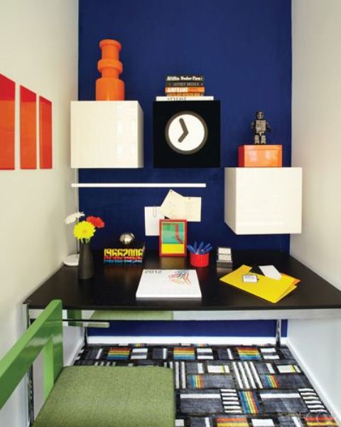 a home office nook with a navy wall and white drawers that create a bold color blocking effect