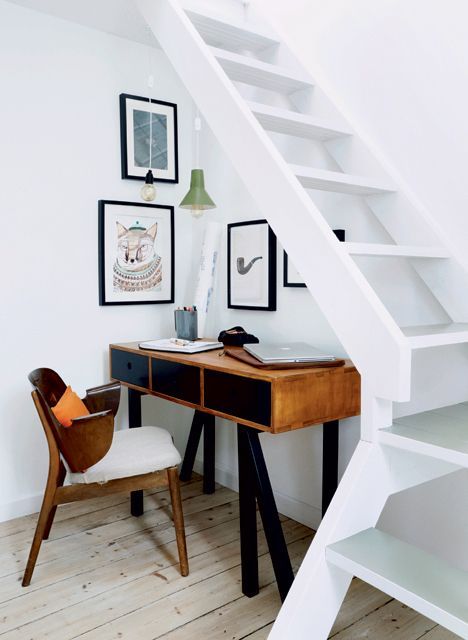 A little and a stylish home office space with mid century modenr furniture and artworks located under the stairs