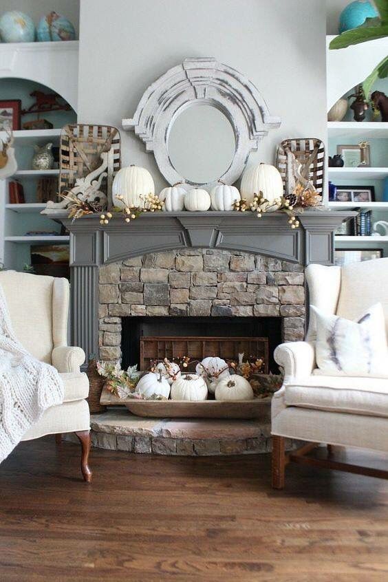 a mantel with white pumpkins and berries, a bread bowl with white pumpkins and leaves next to the fireplace