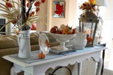 24 an elegant vintage console with faux  pumpkins, leavesm dried blooms and a metal basket with pumpkins