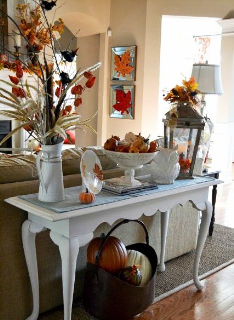 an elegant vintage console with faux  pumpkins, leavesm dried blooms and a metal basket with pumpkins
