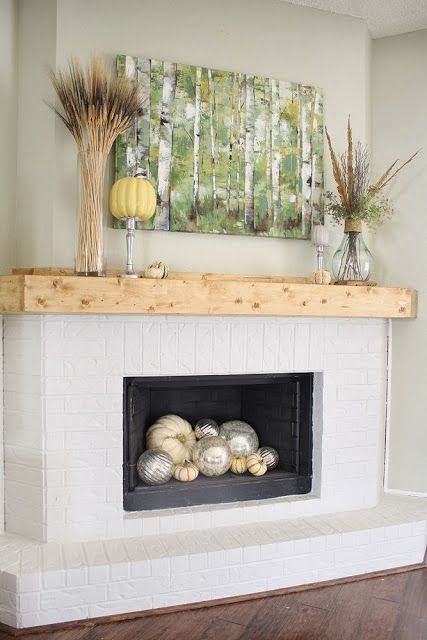 simple styling with a birch artwork, feathers, wheat, pumpkins and silver and white pumpkins in the fireplace