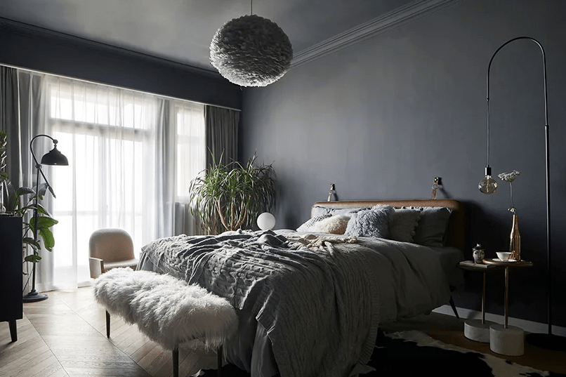 The master bedroom is grey, with a leather upholstered bed, a faux fur bench, some comfy furniture and a fluffy cloud lamp over it all