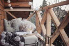 02 candle lanterns, lights garlands, a seat with fluffy pillows and tassel blanket for a contemporary terrace look