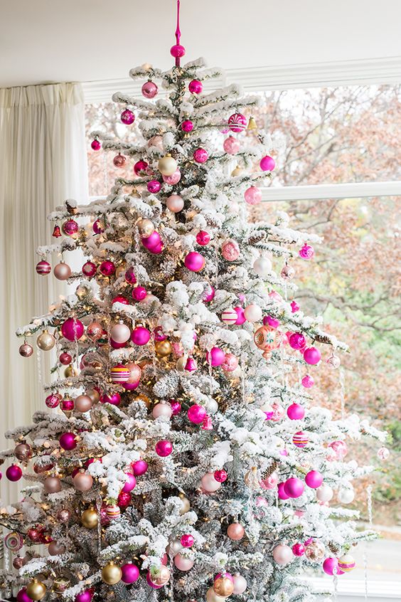 super bold fuchsia and gold ornaments stand out a lot on a flocked tree