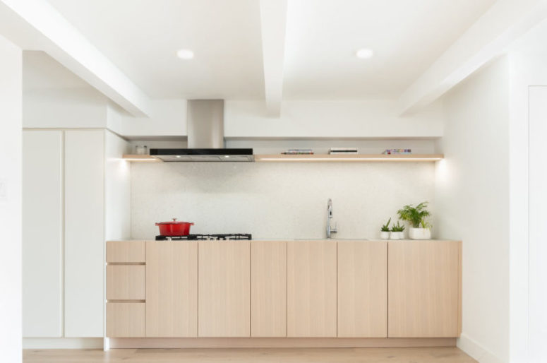 The kitchen is a minimalist space done with light-colored cabinets and white ones, with a neutral backsplash