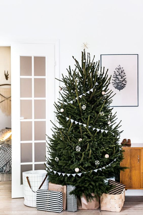 a modern Scandi tree with buntings, white and wooden ornaments and a star on top plus lights