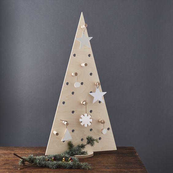 A pegboard Christmas tree with plywood ornaments hanging on hooks is an ultra modern idea to DIY