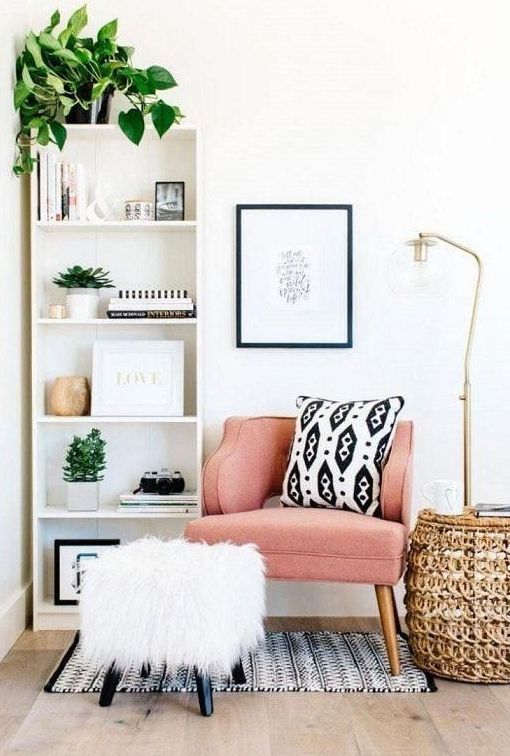 a shelving unit, a comfy chair with a fluffy footrest, a wicker coffee table and a floor lamp