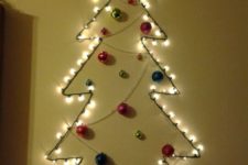 03 a wall-mounted tree made of lights, beads and colorful ornaments plus a glitter star for an entryway or another space
