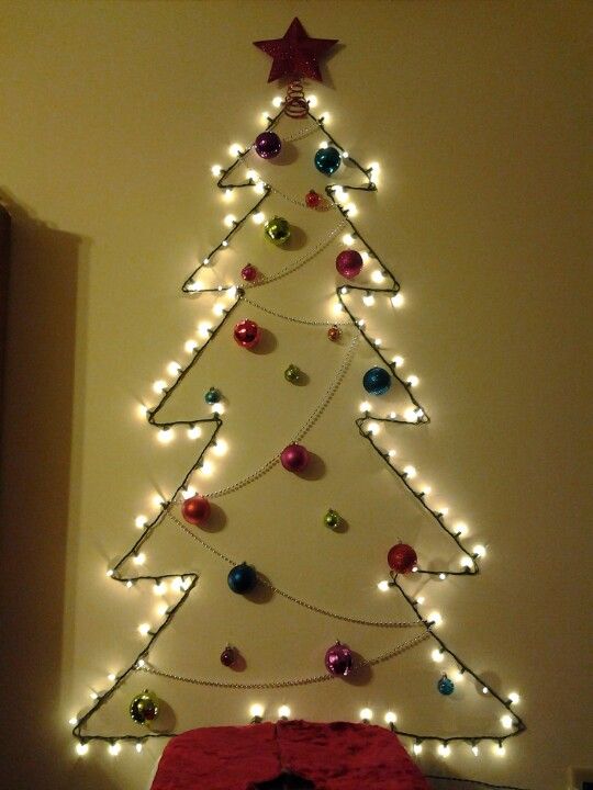 A wall mounted tree made of lights, beads and colorful ornaments plus a glitter star for an entryway or another space