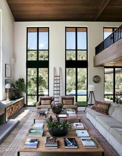 a welcoming modern rustic living room in neutrals, with double height windows and an airy feeling