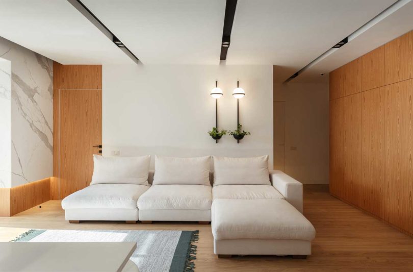 The living room is airy and light filled, with a large sofa and wall lamps