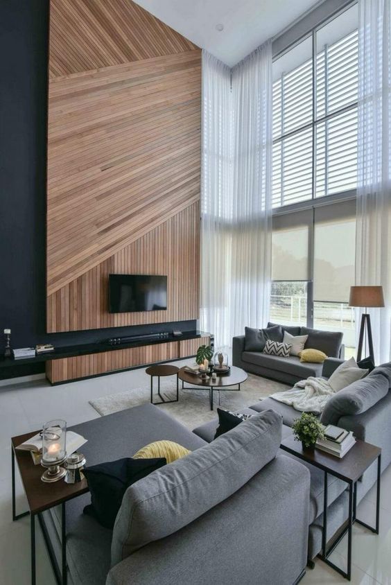 a gorgeous contemporary space with oversized windows, a geometric wood clad TV wall and comfy furniture