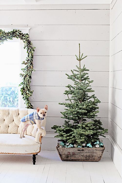 a small Christmas tree placed into a wooden crate filled with emerald ornaments is a modern farmhouse idea