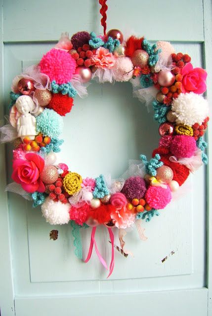 a colorful and whimsy Christmas wreath of pompoms, fake birds, ornaments, ribbons and roses
