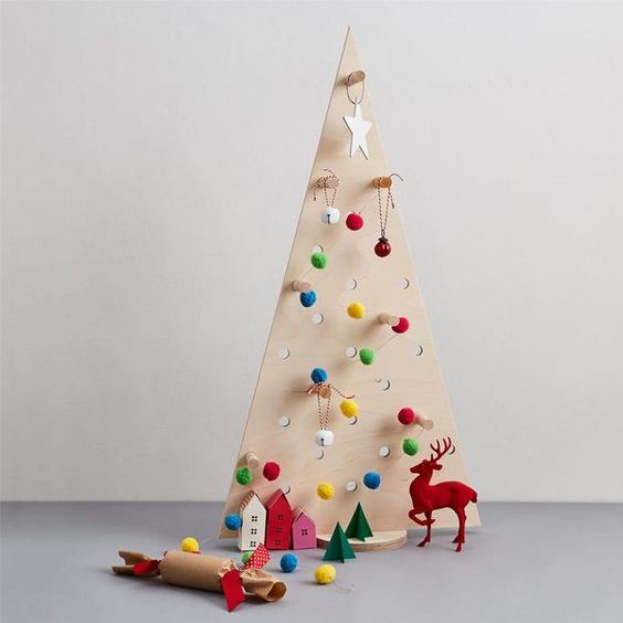 a little pegboard Christmas tree with pompom and jingle bell ornaments hanging on hooks