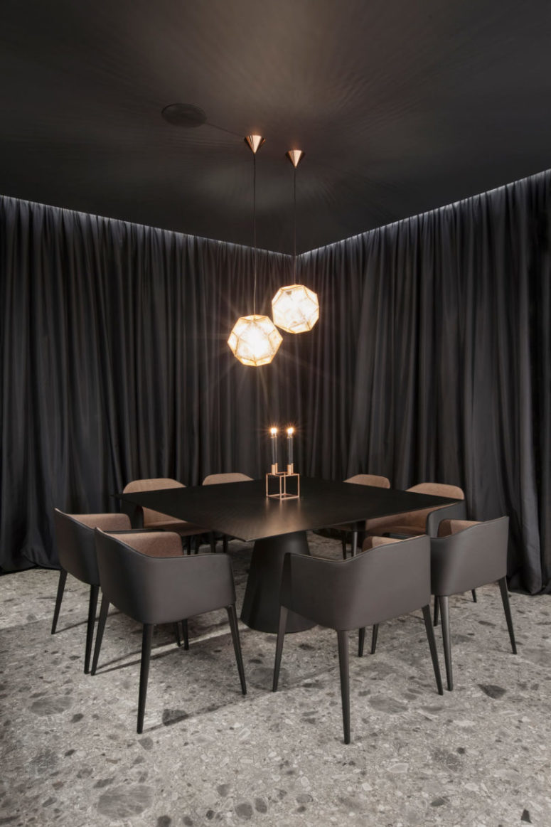 The dining space is done with a square metal table and comfortable modern chairs with upholstery, look at the gorgeous faceted lamps over them