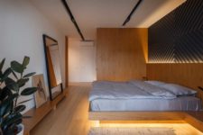06 The master bedroom is done with light-colored wood, a platform bed with lights and a geometric artwork