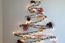 06 a cool wall-mounted Christmas tree of branches, lights and with pinecones and goldd ornaments as an alternative tree