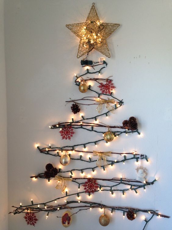 A cool wall mounted Christmas tree of branches, lights and with pinecones and goldd ornaments as an alternative tree
