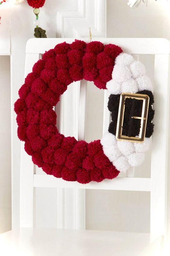 a red, black and white pompom Santa-inspired wreath with a large buckle is a fun idea instead of a usual greenery one