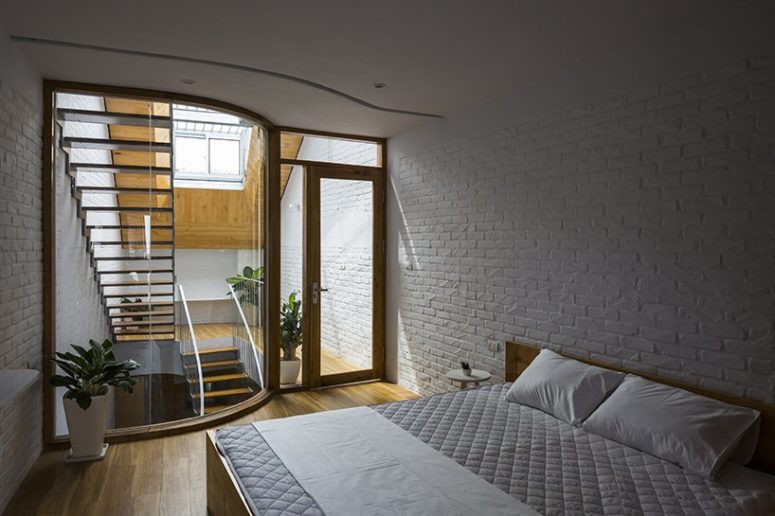 The bedroom is a simple space with a large bed, bedside tables and some plants