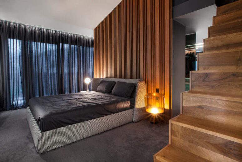 The master bedroom features a wooden wall, a glazed wall that can be covered with curtains and mismatching bedside tables