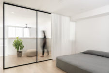 07 The minimalist bedroom is divided from the rest of the space with glass and there’s a large bed