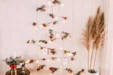 07 a boho wall-mounted Christmas tree of lights, berries and Christmas cards plis pampas grass and blooms around