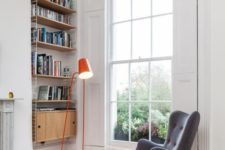 07 a colorful floor lamp, an upholstered chair with a footrest, a shelving unit on the wall and firewood