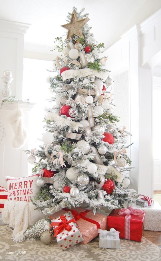 a flocked Christmas tree decorated with white, silver and red ornaments plus ribbons and banners