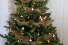 07 a simple rustic Christmas tree in a basket with silver ornaments, lights and burlap ribbons all over it