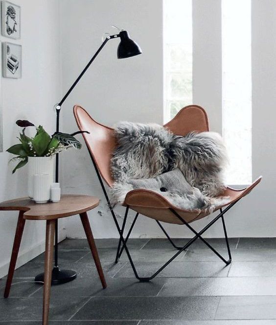 a chic modern chair of leather, a wooden side table and a floor lamp that matches the chair frame
