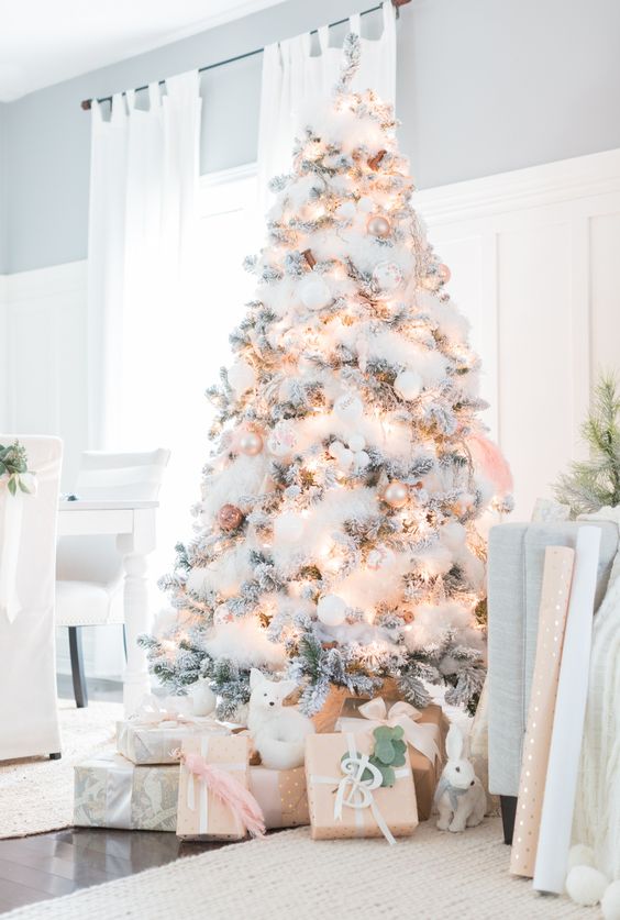 a flocked Christmas tree with cotton, lights, white and pearly ornaments plus figurines under