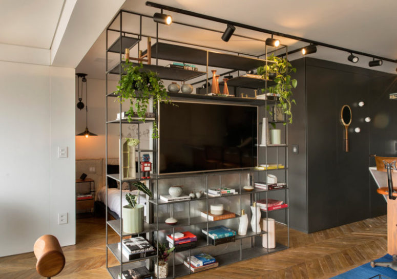 The floor to ceiling shelving unit divides the spaces and hides the sleeping zone