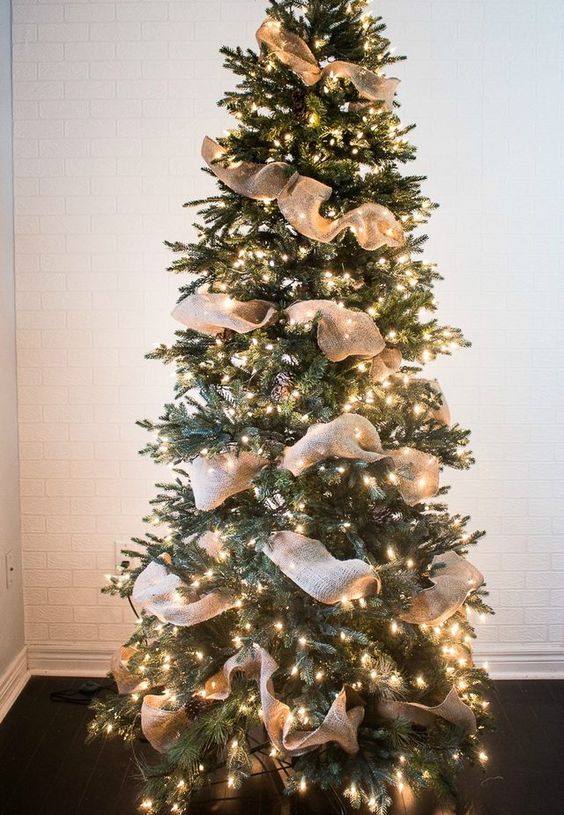 A simple rustic Christmas tree idea with pinecones, burlap ribbons and lights all over   you won't need more