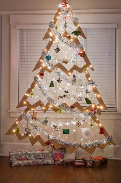 a hanging Christmas tree of plywood decorated with lights, ornaments and garlands for a creative look