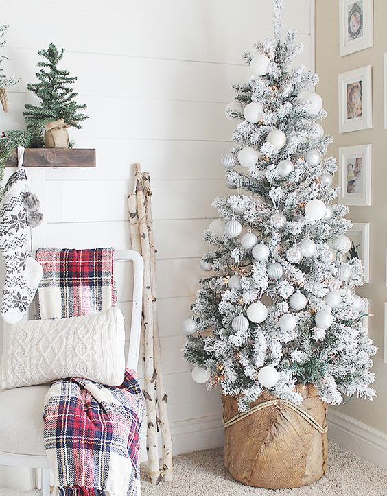 a snowy Christmas tree decorated with pearly, grey and silver ornaments and a base wrapped with burlap