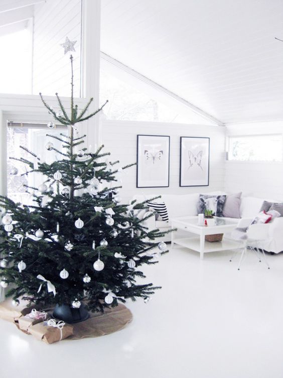 a modern Nordic Christmas tree with white ornaments plus bows and a star on top