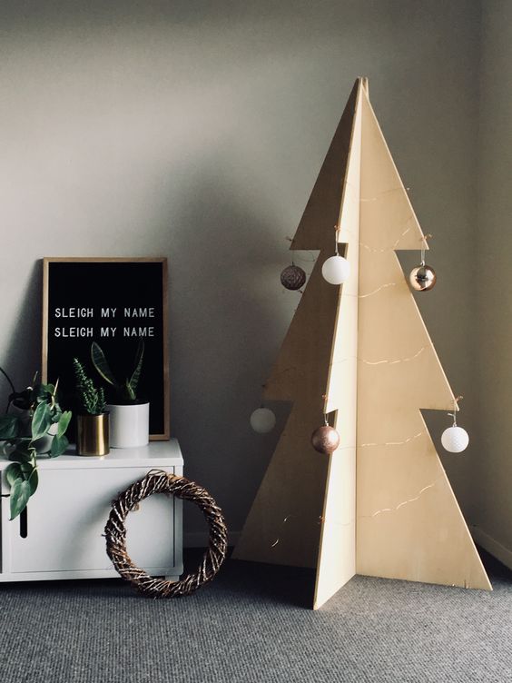 a large plywood Christmas tree decorated with several ball ornaments on each side for a minimalist look